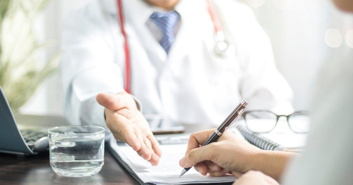 Paciente firmando un formulario de consentimiento junto a un profesional de salud